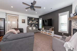 Living room featuring ceiling fan, a fireplace, and light carpet