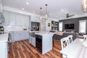 Kitchen featuring a center island with sink, decorative light fixtures, dark hardwood / wood-style floors, and stainless steel appliances