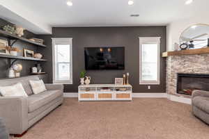 Carpeted living room with a fireplace and a healthy amount of sunlight