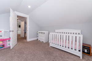 Bedroom with carpet flooring, vaulted ceiling, and a nursery area