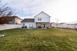 Rear view of house with a patio area, a yard, and central AC