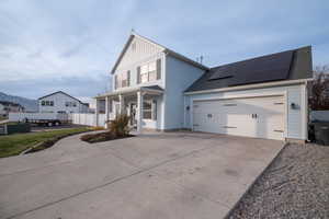 View of front facade with solar panels, a porch, and a garage