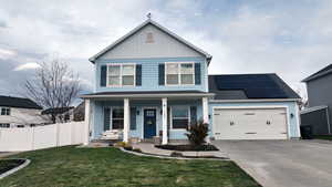 View of front of home with covered porch, solar panels, a garage, and a front lawn