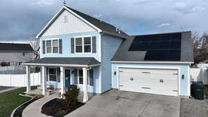 Front facade with a garage, a porch, and solar panels