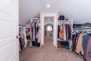 Walk in closet featuring light colored carpet and vaulted ceiling