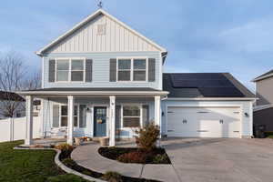 View of front of property featuring a garage, a porch, and solar panels