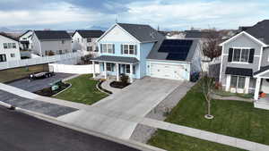 View of front facade featuring solar panels, covered porch, and a front lawn