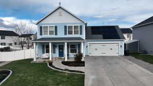 View of front of house with solar panels, central AC, a front yard, covered porch, and a garage