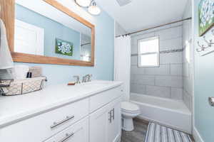 Full bathroom featuring shower / bath combo with shower curtain, hardwood / wood-style floors, vanity, and toilet