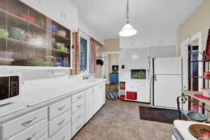 Kitchen featuring sink, tile countertops, decorative light fixtures, white appliances, and white cabinets