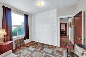 Bedroom with a closet, radiator heating unit, and dark wood-type flooring