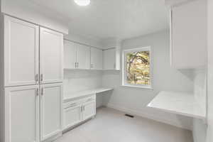 Laundry area featuring light tile patterned floors and crown molding