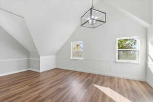 Additional living space with a chandelier, vaulted ceiling, and hardwood / wood-style flooring