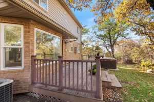 Wooden deck featuring a hot tub and central air condition unit