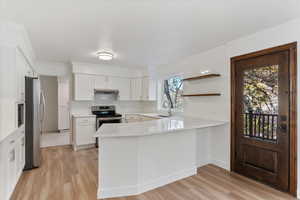 Kitchen featuring kitchen peninsula, appliances with stainless steel finishes, white cabinetry, and a wealth of natural light