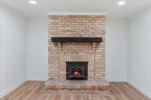 Interior details with a brick fireplace, wood-type flooring, and ornamental molding