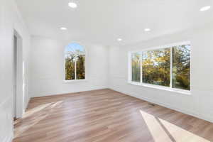 Empty room with a healthy amount of sunlight, crown molding, and light hardwood / wood-style flooring