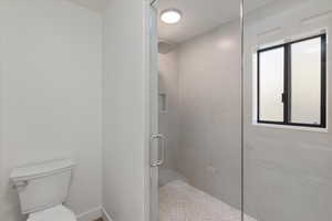 Bathroom featuring walk in shower, toilet, and a wealth of natural light