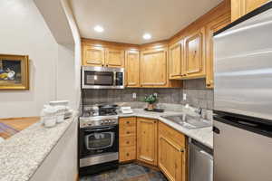 Kitchen featuring tasteful backsplash, sink, and appliances with stainless steel finishes