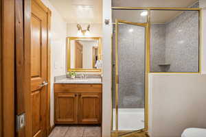 Bathroom featuring tile patterned flooring, vanity, toilet, and an enclosed shower