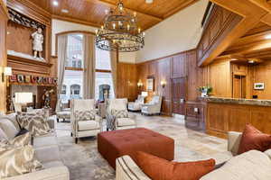 Living room featuring wood walls, crown molding, a towering ceiling, beamed ceiling, and wood ceiling