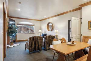 Carpeted dining space featuring ornamental molding and a textured ceiling
