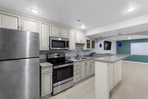 Kitchen featuring pendant lighting, sink, stainless steel appliances, and a textured ceiling