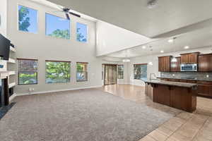 Kitchen featuring a high ceiling, decorative light fixtures, a kitchen island with sink, a breakfast bar, and light tile patterned floors