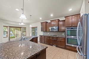 Kitchen featuring hanging light fixtures, dark stone countertops, sink, and stainless steel appliances