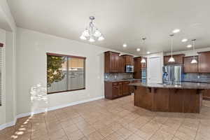 Kitchen featuring dark stone counters, hanging light fixtures, appliances with stainless steel finishes, and an inviting chandelier