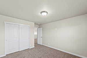 Unfurnished bedroom with carpet, a textured ceiling, and a closet