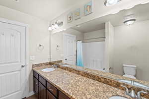 Bathroom featuring walk in shower, vanity, and toilet