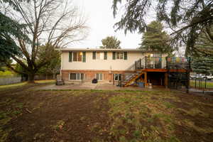 Rear view of house with a wooden deck and a patio