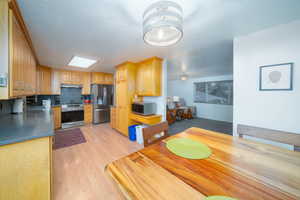 Kitchen with backsplash, sink, light brown cabinetry, light hardwood / wood-style floors, and stainless steel appliances