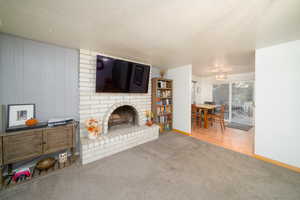 Unfurnished living room with wood-type flooring, a textured ceiling, and a brick fireplace