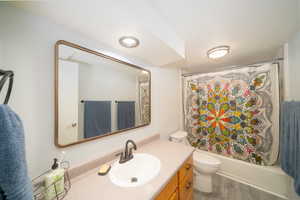 Full bathroom with hardwood / wood-style floors, vanity, toilet, and shower / tub combo with curtain