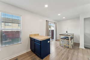 Kitchen with blue cabinets, kitchen peninsula, and light hardwood / wood-style flooring