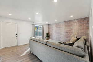 Living room featuring wood-type flooring and brick wall