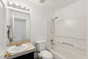 Full bathroom featuring toilet, vanity, a textured ceiling, and tub / shower combination