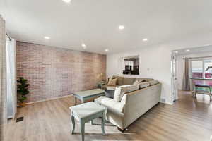 Living room featuring brick wall and light wood-type flooring