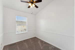 Empty room featuring ceiling fan, carpet floors, and vaulted ceiling