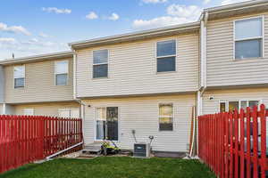 Back of house featuring a lawn and central air condition unit