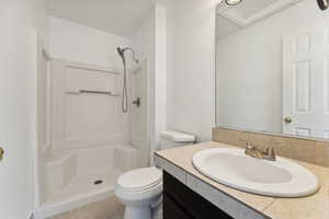 Bathroom with tile patterned flooring, vanity, toilet, and walk in shower