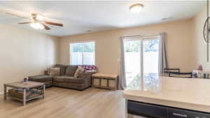 Living room with ceiling fan, a textured ceiling, and light hardwood / wood-style flooring