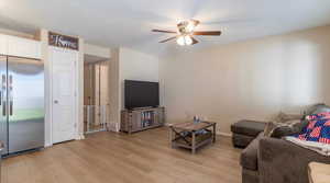 Living room featuring ceiling fan, light hardwood / wood-style floors, and a textured ceiling