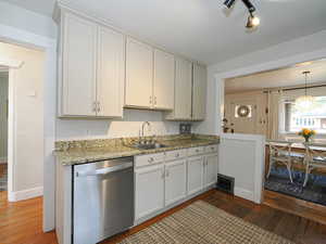 Kitchen with dishwasher, dark hardwood / wood-style floors, white cabinetry, and sink