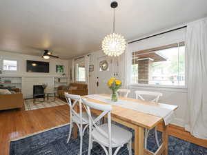 Dining room featuring dark hardwood / wood-style floors, a healthy amount of sunlight, a wood stove, and ceiling fan with notable chandelier