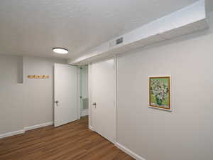 Basement with dark hardwood / wood-style flooring and a textured ceiling