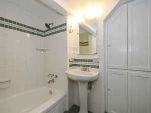 Bathroom featuring tiled shower / bath combo and tile walls