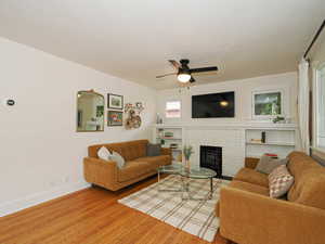 Living room with ceiling fan, a fireplace, and wood-type flooring